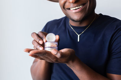 Midsection of man holding pills against white background