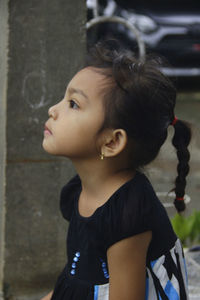 Side view of young woman looking away against wall