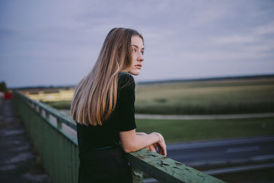 Woman standing on a road bridge during sunset