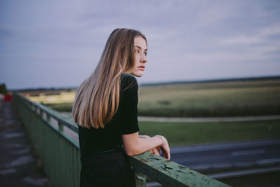 Woman standing on a road bridge during sunset