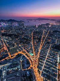 Aerial view of illuminated cityscape against sky during sunset