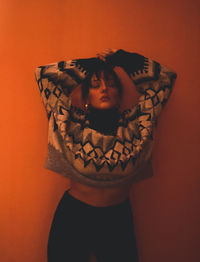 Portrait of woman standing against orange wall