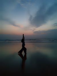 Silhouette man on beach against sky during sunset