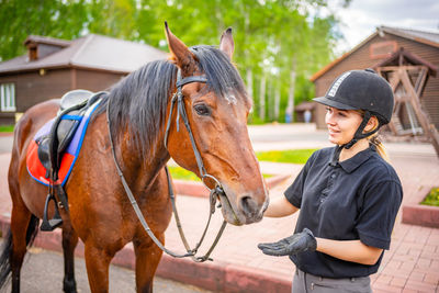 Young woman with horse standing outdoors