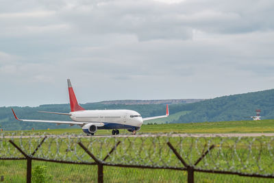 A civilian passenger plane with turbojet engines accelerates along the runway on the airport field