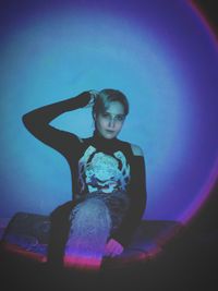 Side view of young woman sitting on wall