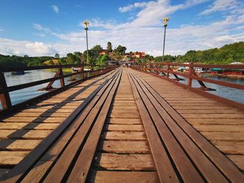 Surface level of wooden bridge against sky