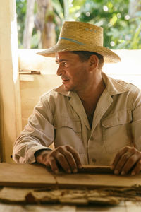 Man wearing hat making tobacco product on table