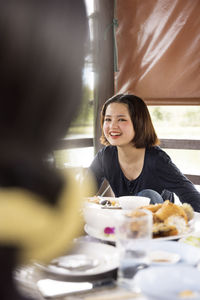 Smiling teenage girl sitting at dining table outdoors