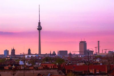 Fernsehturm tower amidst buildings in city against sky during sunset