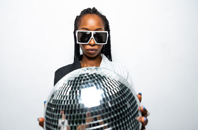 Portrait of young woman wearing sunglasses against white background