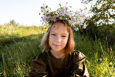 Child with a wreath on his head. girl in a dress and a straw hat. wellness and freedom concept.