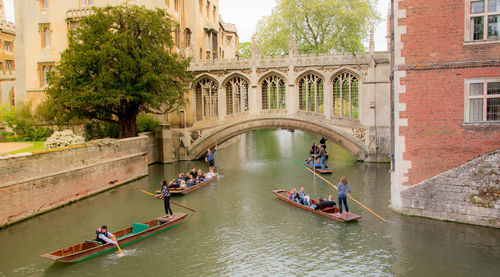 People on boat in canal amidst buildings