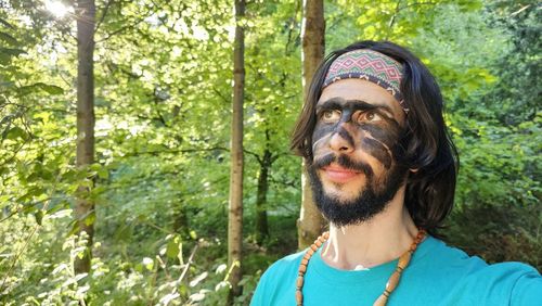 Portrait of young woman standing against trees