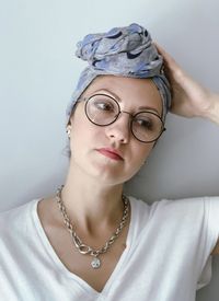 Portrait of woman wearing eyeglasses against wall