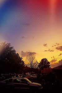 Silhouette of cars parked by trees against sky during sunset