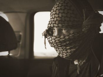 Close-up of man covering face with scarf in car