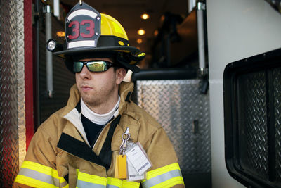 Close-of firefighter looking away while sitting at fire engine