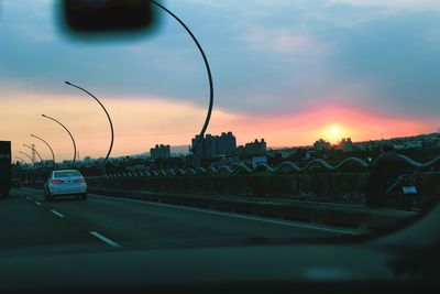 Cars on road against sky during sunset