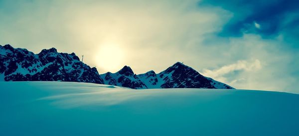 Snow covered landscape against cloudy sky