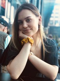 Portrait of smiling young woman sitting at sidewalk cafe