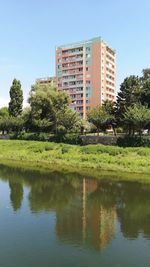 Reflection of trees and buildings in lake against sky