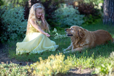 Cute girl crouching by golden retriever in back yard