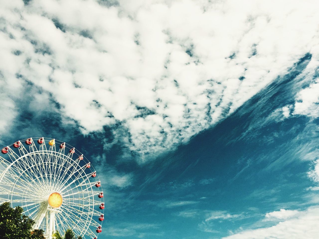 sky, arts culture and entertainment, low angle view, amusement park, ferris wheel, amusement park ride, cloud - sky, cloudy, multi colored, outdoors, celebration, no people, nature, fun, pattern, day, cloud, circle, illuminated, beauty in nature