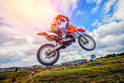 Low angle view of man riding bicycle on field against sky