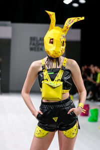 Midsection of woman holding yellow mask