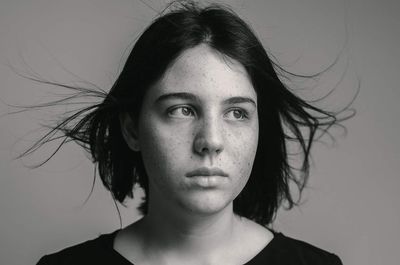 Close-up of thoughtful teenage girl with tousled hair looking away