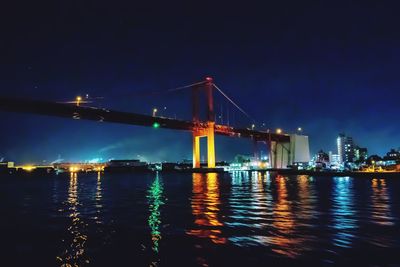 Illuminated suspension bridge over river at night