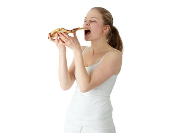 Young woman eating food against white background