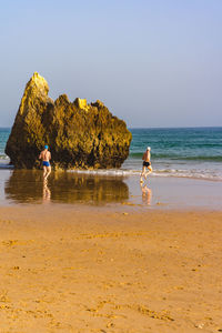 People on beach against clear sky