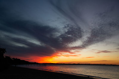 Scenic view of sea against dramatic sky during sunset