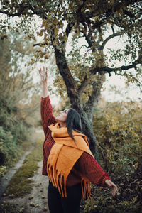 Woman standing by tree against plants