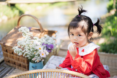 Portrait cute girl eating food while sitting at park