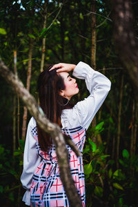 Woman standing by tree in forest