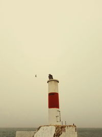 View of lighthouse by sea against clear sky