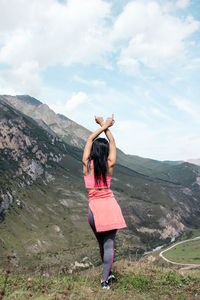 Rear view of woman standing on landscape against mountain