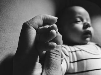 Cropped image of parent holding son hand at home