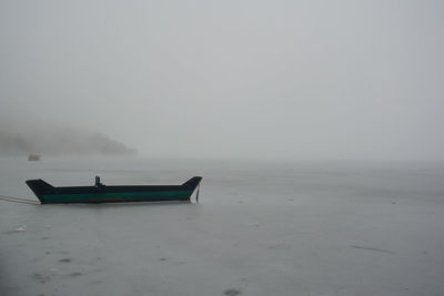 Scenery with a wooden boat in the frozen lake a foggy day