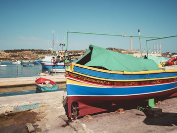 Boats moored at beach against clear blue sky