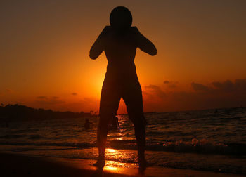 Silhouette man standing at beach during sunset