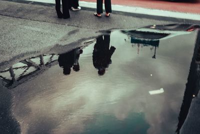 Low section of woman walking in puddle on street