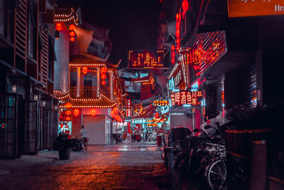 Illuminated street amidst buildings in city at night