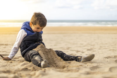 Cute boy sitting at shore of beach