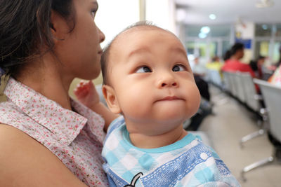 Close-up of baby boy with mother suffering from cross-eyed at hospital