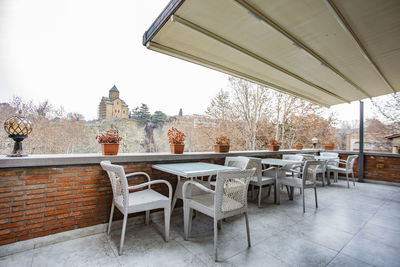 Empty chairs and tables against clear sky during winter