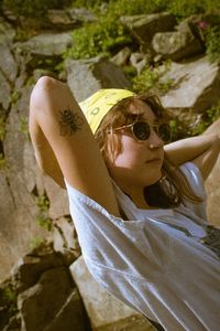 Midsection of woman with sunglasses on rock